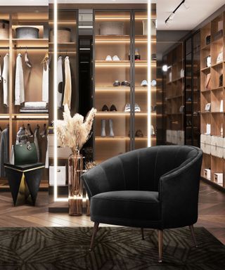 luxury closet with shelf lighting and black armchair