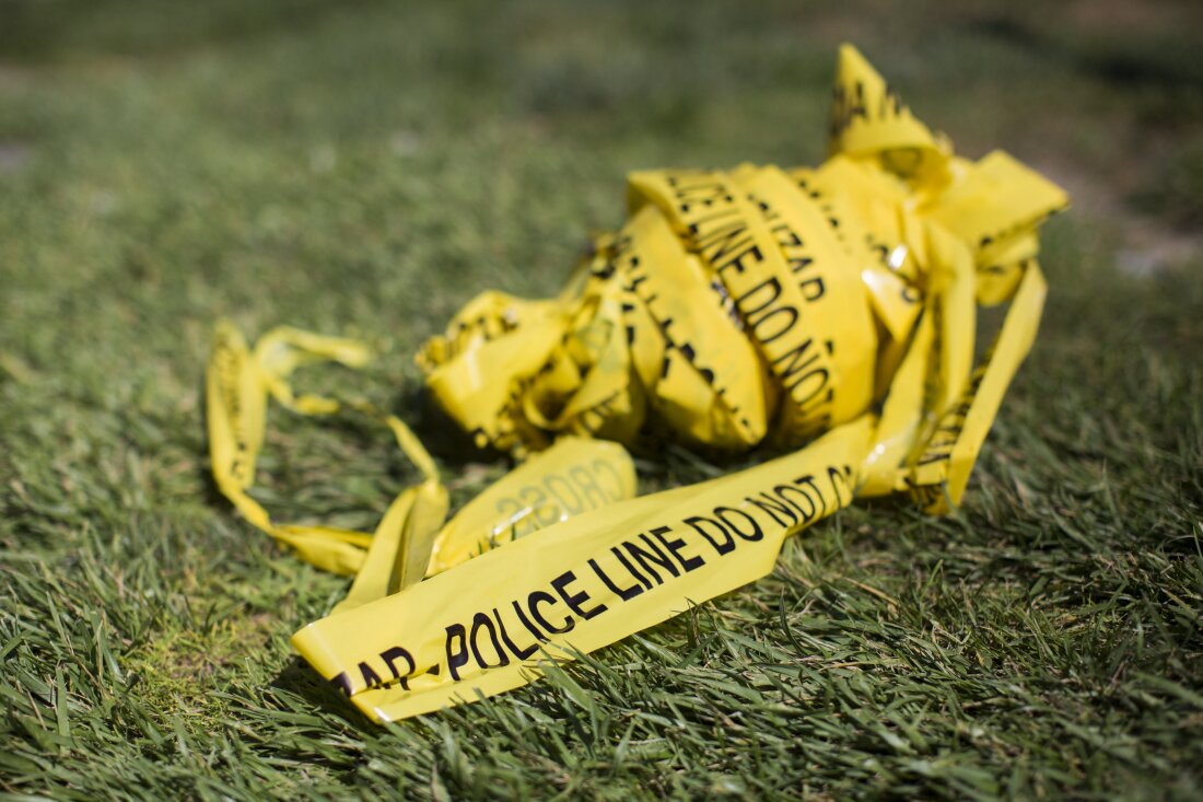 Yellow police tape sits balled on the grass.