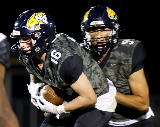 Neuqua Valley's QB Kiet Truong, right, hands the ball to Andrew Barkley during the game against DeKalb in Naperville on Friday, Sept. 27, 2024. (James C. Svehla / Naperville Sun)