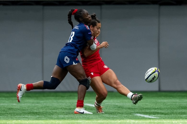 A woman rugby player kicks the ball.