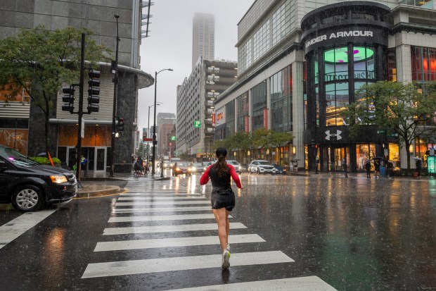 A person runs down Michigan Avenue during heavy rain in Chicago on Sept. 24, 2024. (Tess Crowley/Chicago Tribune)