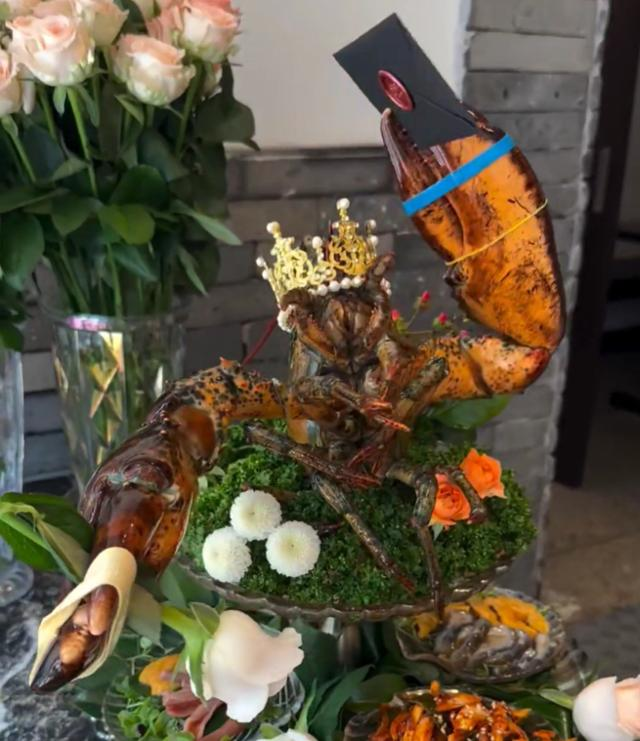 A lobster with its lower body severed, holding an envelope and a flower in its claws, is seen waving its claws on a plate, served at a restaurant in Seoul. Captured from online community