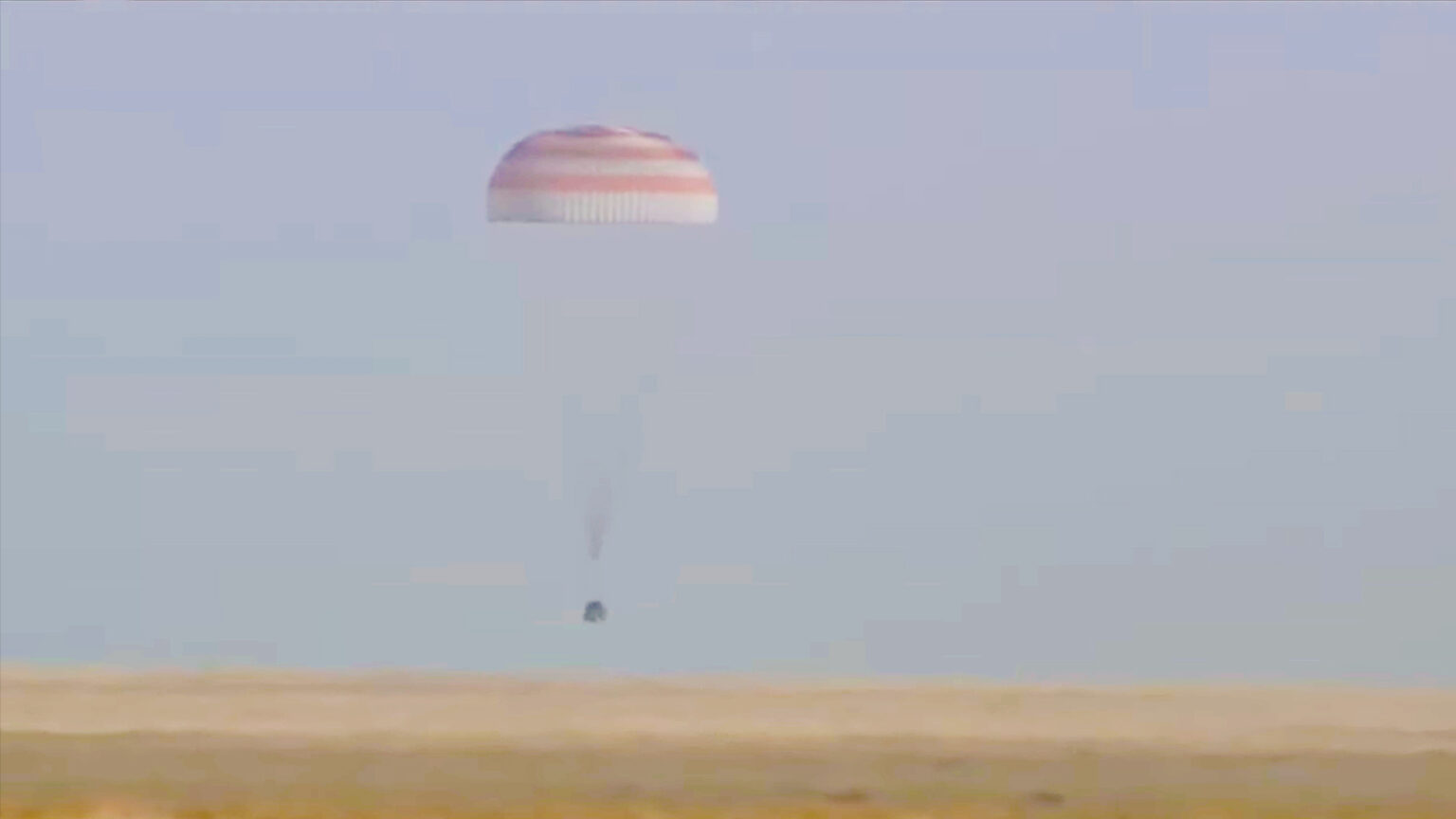 The Soyuz MS-25 lander parachuting down to the surface of the steppe of Khazakstan