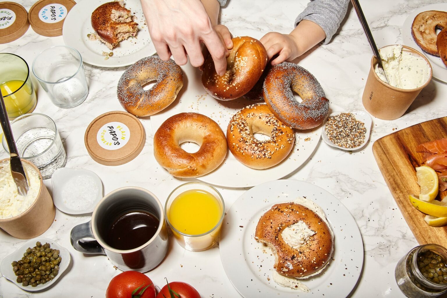 Image may contain Brunch Food Cup Plate Bread Person Banana Fruit Plant Produce Bagel Dining Table and Furniture