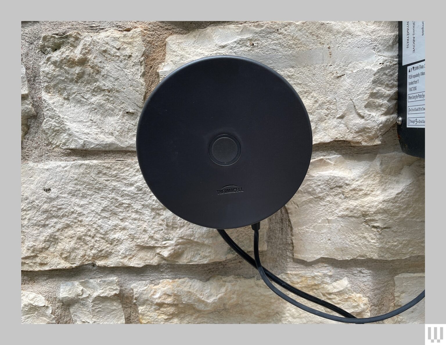 Black discshaped device attached to a stone wall