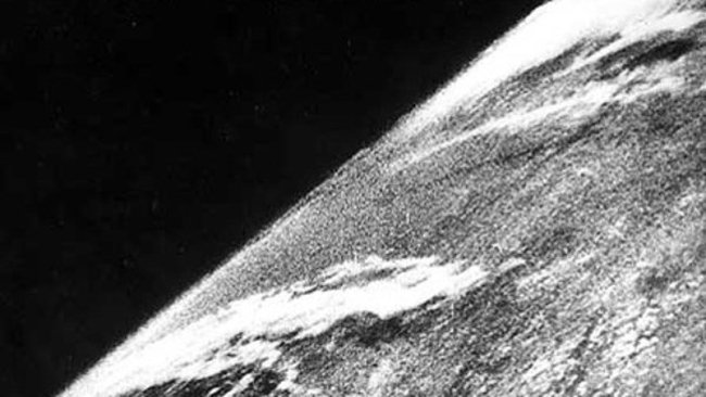 Black-and-white photo of small portion of the edge of Earth with some clouds and black space.