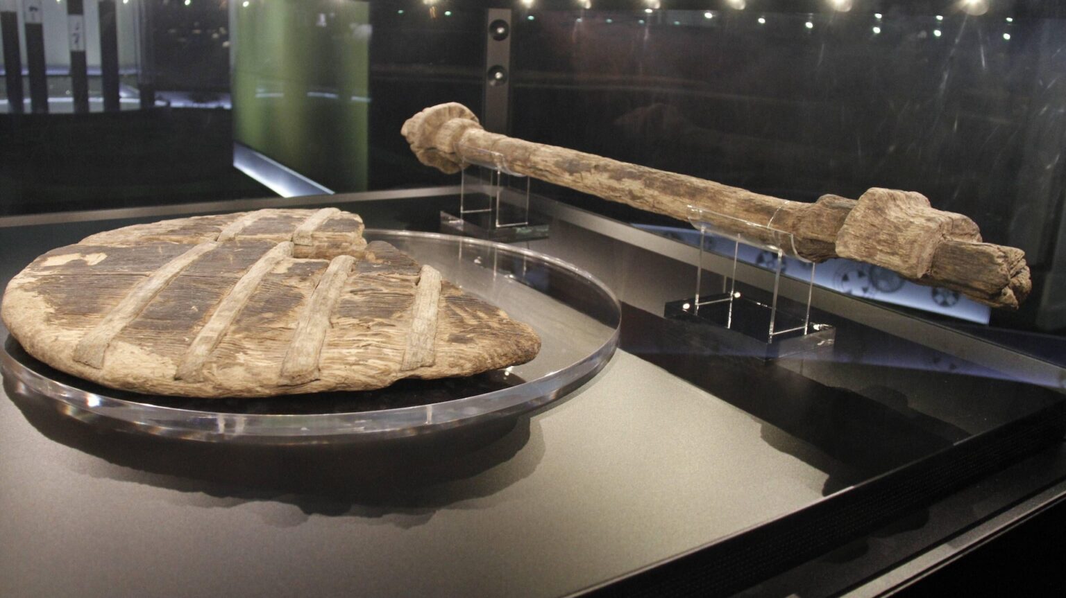 A photograph of an ancient wooden wheel in a museum exhibit