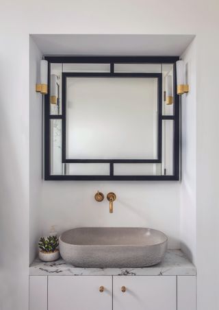 A bathroom with a square mirror, with light sconces on either side