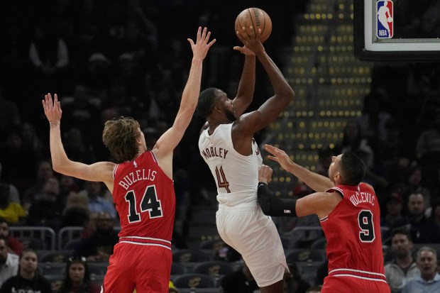 Cleveland Cavaliers forward Evan Mobley (4) shoots between Chicago Bulls forward Matas Buzelis (14) and center Nikola Vucevic (9) in the first half of a preseason NBA basketball game, Tuesday, Oct. 8, 2024, in Cleveland. (AP Photo/Sue Ogrocki)