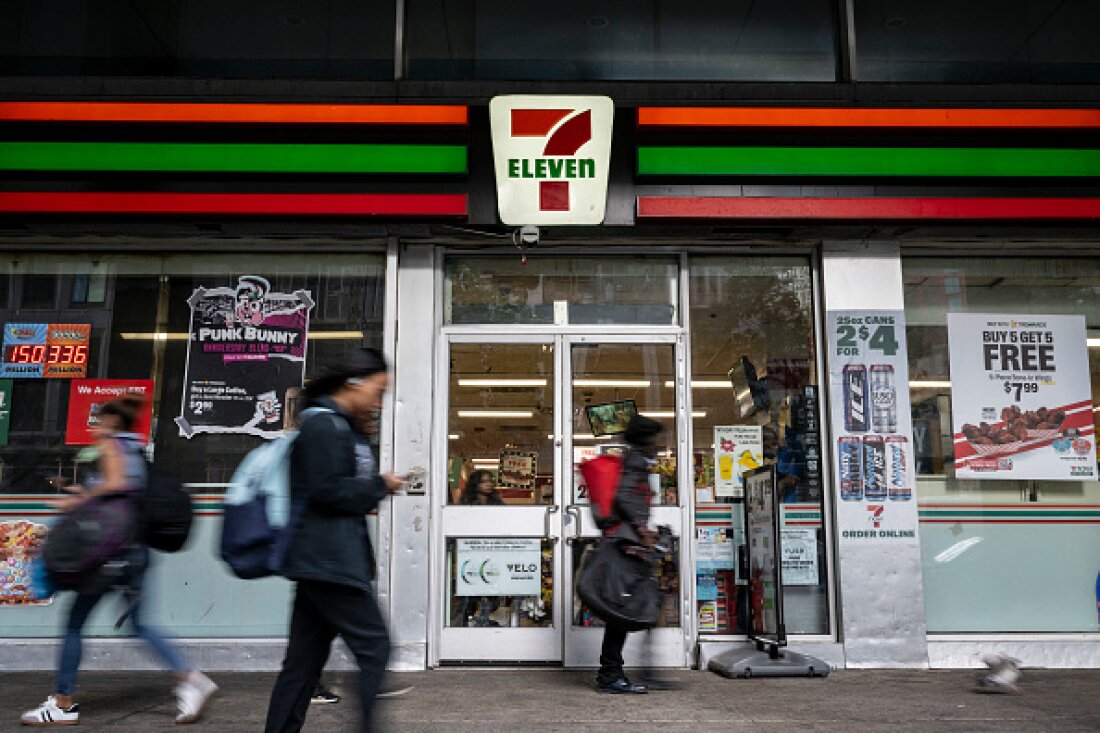 People walk past a 7-Eleven convenience store in New York City on Wednesday. The company plans to shut down 444 stores across North America to recoup costs lost to inflation, a drop in store traffic and declining cigarette sales.