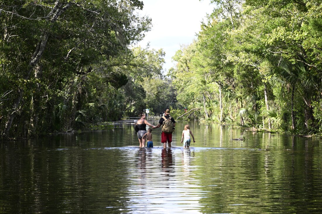 Dustin Holmes, second from right, holds hands with his girlfriend, Hailey Morgan, while returning to their flooded home with her children Aria Skye Hall, 7, right, and Kyle Ross, 4, in the aftermath of Hurricane Helene, Friday, Sept. 27, 2024, in Crystal River, Fla.