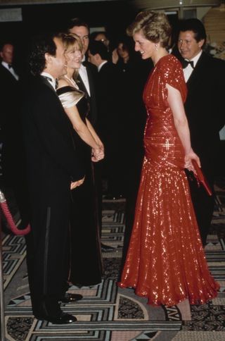 Princess Diana wearing a red evening gown talking to Billy Crystal and Meg Ryan at the premiere of 'When Harry Met Sally.'