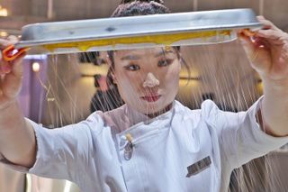 Jung Ji-sun holds up a kitchen utensil as she makes sugar strings, in Culinary Class Wars.