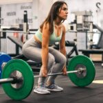 woman athlete doing deadlift in a gym. side view