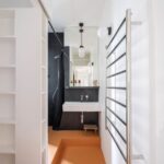 white bathroom with black walls and orange flooring.