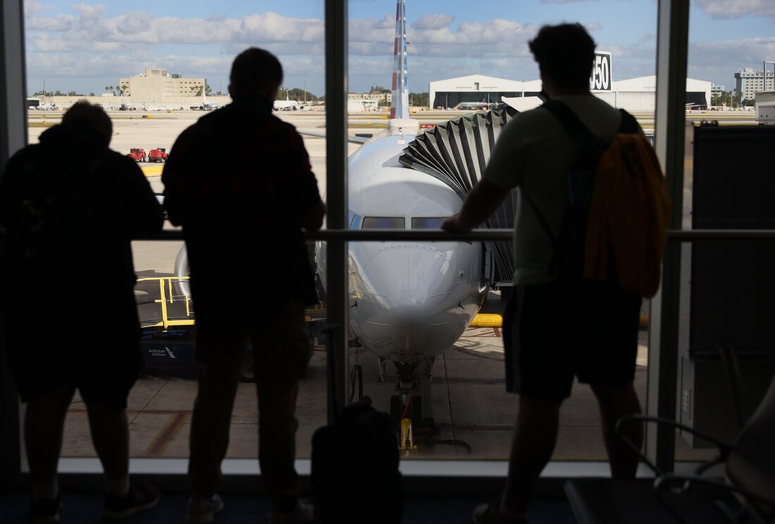 Passengers look out at an American Airlines jet.