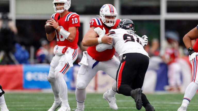 New England Patriots center Ben Brown (77) holds off Houston Texans defensive tackle Folorunso Fatukasi (91) as New England Patriots quarterback Drake Maye (10) looks to throw during the second quarter at Gillette Stadium.