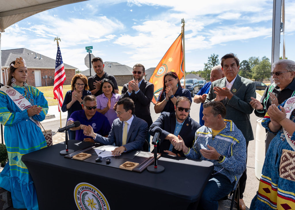 Representatives of the Cherokee Nation, including Principal Chief Chuck Hoskin Jr., shake hands after signing an extension...