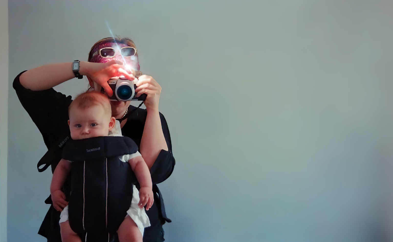 Victoria Mapplebeck holds her son Jim in a baby carrier as she takes a photograph of them in what is presumably a mirror