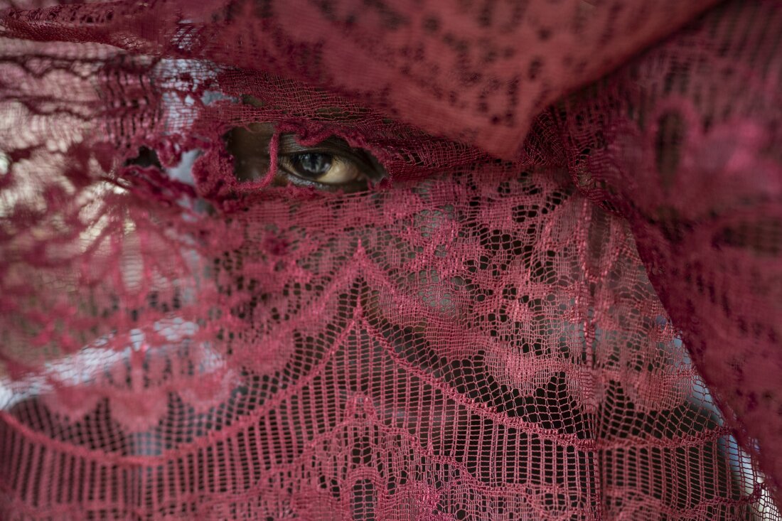 Camilo Garcia peeks through a curtain of his house on the morning of March 29, 2024, in the town of Juntas, Buenaventura, Colombia. The community gathers during Holy Week to celebrate the Manacillos festival, an ancestral ritual originating in the upper part of the Yurumangui River. Photographer: Nathalia Angarita