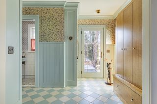 an entryway with pale blue paneling and bee wallpaper