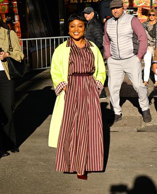 A photo of Quinta Brunson in a dark red dress with stripes.