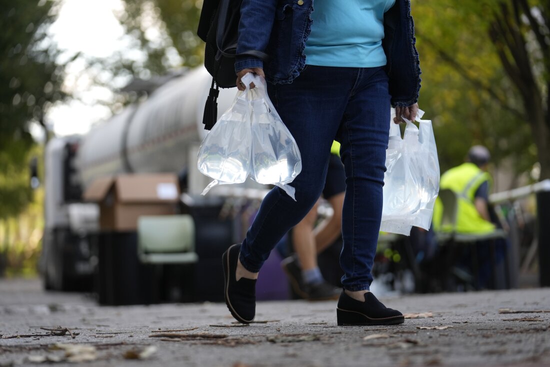 A person carries bags of fresh water after filling up from a tanker at a distribution site in the aftermath of Hurricane Helene on Wednesday in Asheville, N.C.