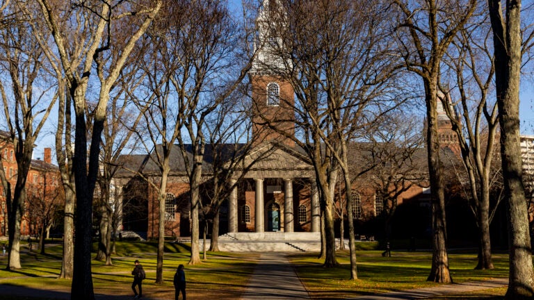 A pedestrian walks through Harvard University’s campus in Cambridge, Mass.