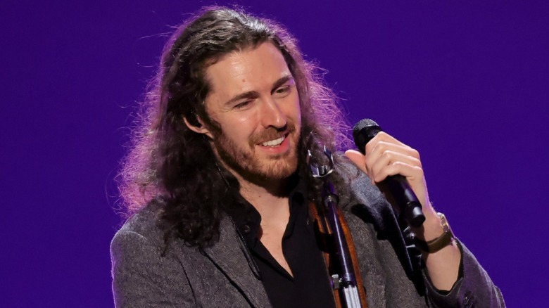 Hozier smiling, holding microphone