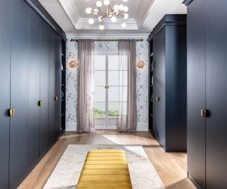 navy blue walk-in closet with yellow ottoman