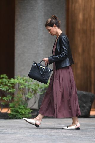 Katie Holmes walks outside in new york city wearing a burgundy dress with white slingback flats and a collarless leather jacket