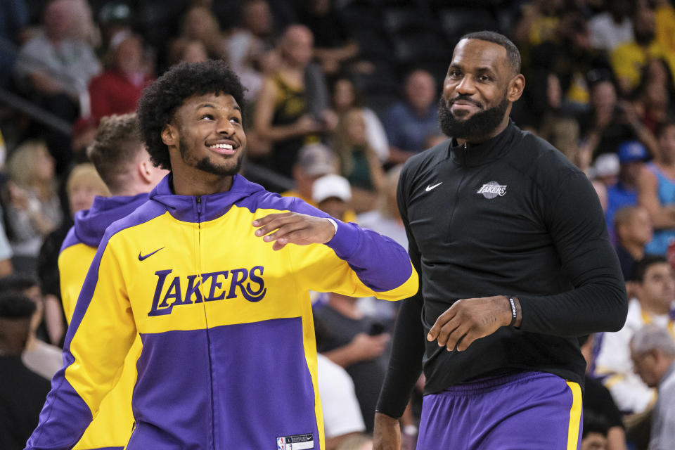 Los Angeles Lakers guard Bronny James, left, and forward LeBron James warm up before a preseason NBA basketball game against the Phoenix Suns, Sunday, Oct. 6, 2024, in Palm Desert, Calif. (AP Photo/William Liang)