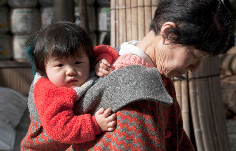 A Japanese baby being carried on his grandmother's back.