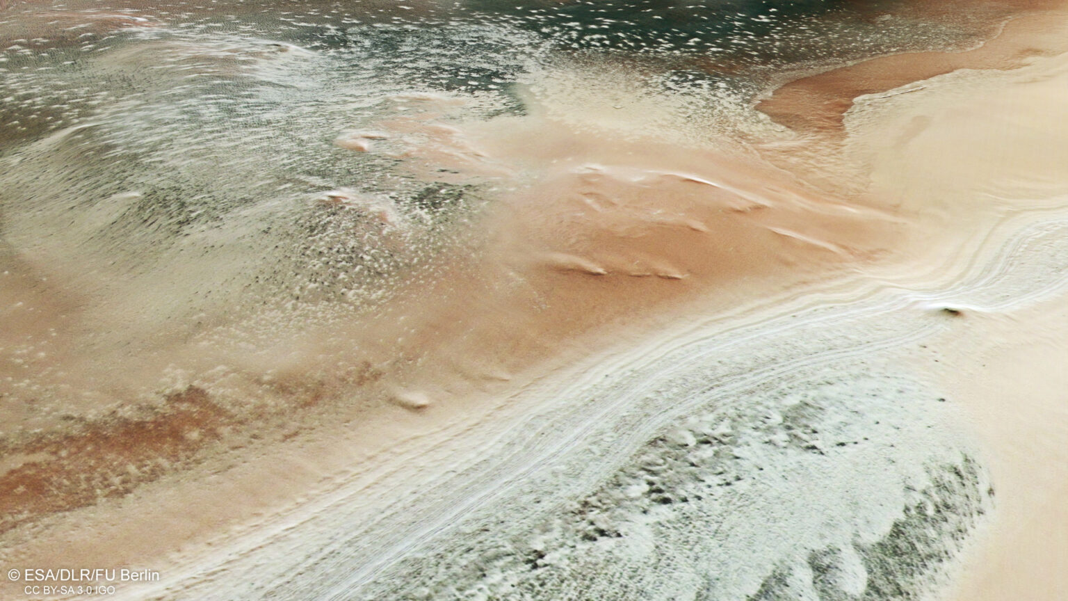 view of mars from orbit showing red sandy regions, white icy terrain and an area dominated by dark rock