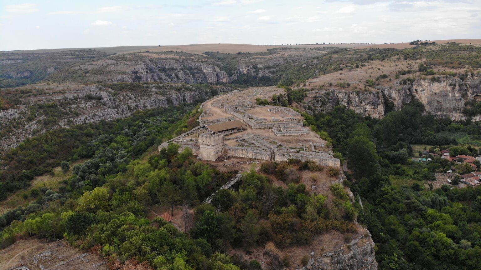 an aerial view of ruins in a rocky forested landscape