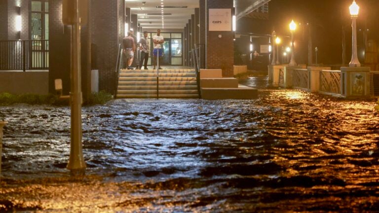 People look out at surge waters flooding the street from their building after Hurricane Milton came ashore in the Sarasota area on October 09, 2024, in Fort Myers, Florida.