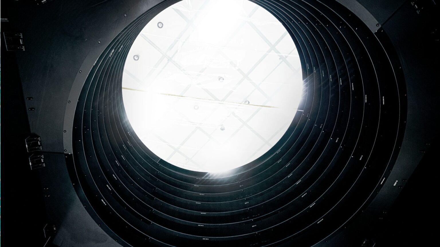 scientists in clean suits work on a large grey rectangle in a cleanroom