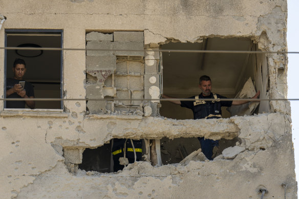 Municipality workers survey the damage to an apartment building struck by a rocket fired from Lebanon, in Kiryat Ata, northern Israel, on Saturday.