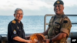 In this undated photo provided by the New Zealand Defense Force, Lieutenant Commander Tala Mafile'o of the Royal Tongan Navy presents Commander Yvonne Gray with a wooden bowl as a memento of the RNZN's participation in the 50th Anniversary Fleet Review.