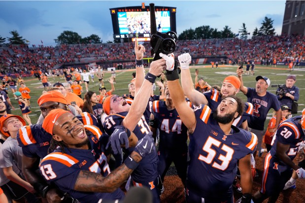 Illinois' Pat Bryant (13), Declan Duley (31) and Devin Hale celebrate with Cannon Trophy a 50-49 overtime victory against Purdue on Oct. 12, 2024, in Champaign. (Charles Rex Arbogast/AP)