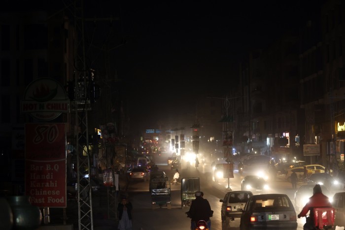 A blacked-out city street illuminated by vehicle lights