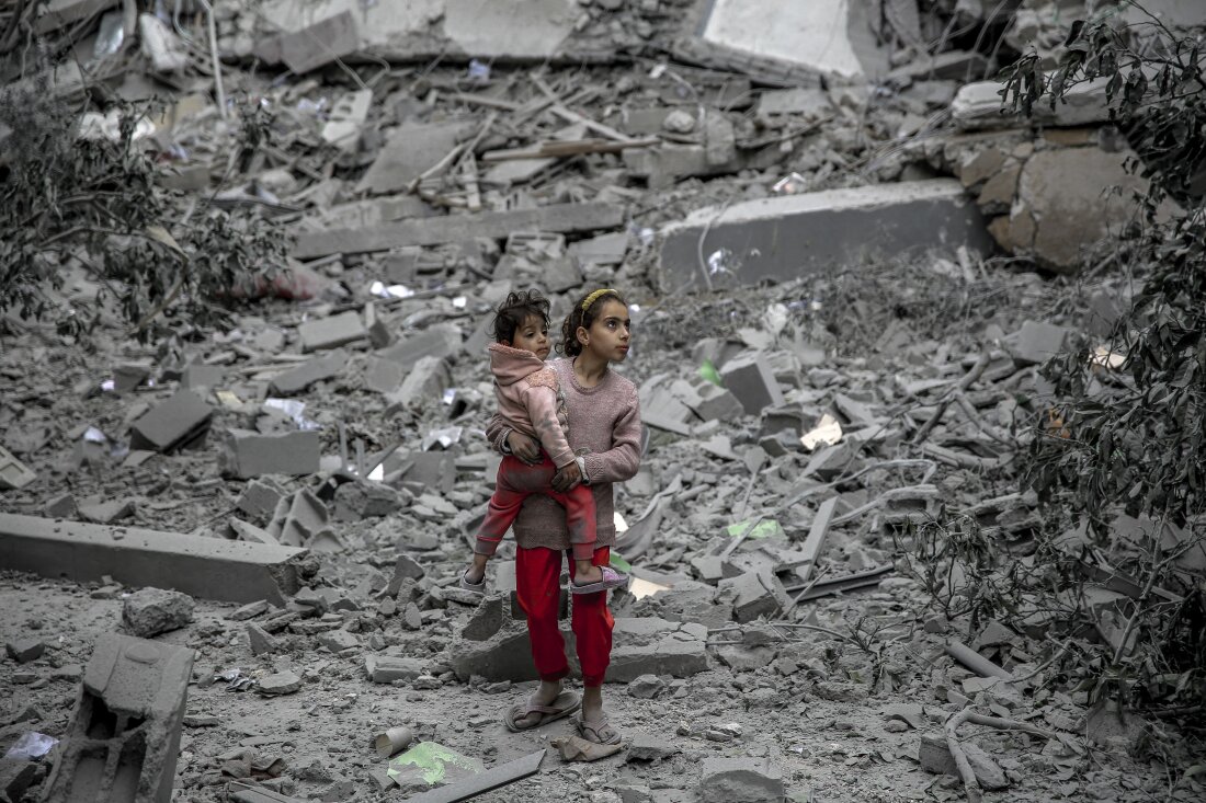 A Palestinian girl carries a child through the rubble of houses destroyed by Israeli bombardment in Gaza City on March 3, 2024, amid the ongoing conflict between Israel and the Hamas movement.