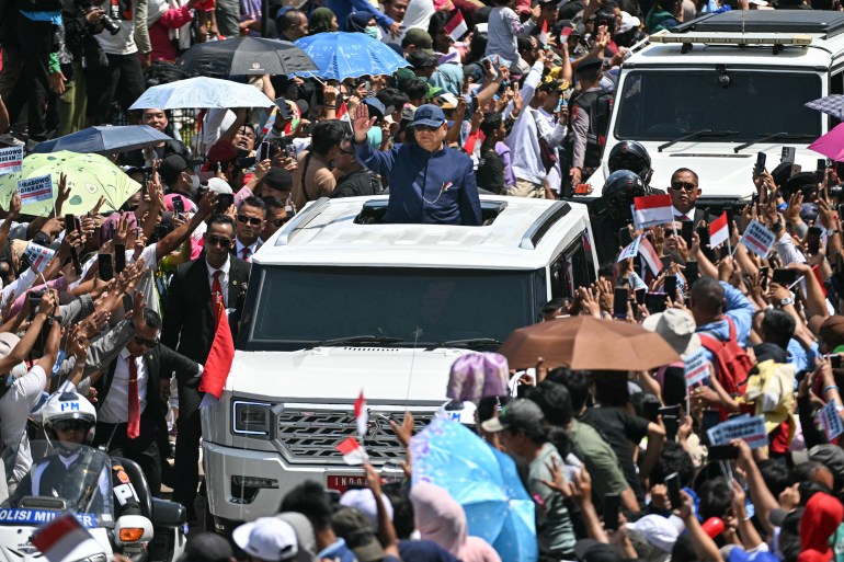 Indonesia's newly sworn-in President Prabowo Subianto (C) waves to his supporters as he heads to the Presidential Palace during the inauguration ceremony in Jakarta on October 20, 2024. (Photo by JUNI KRISWANTO / AFP)