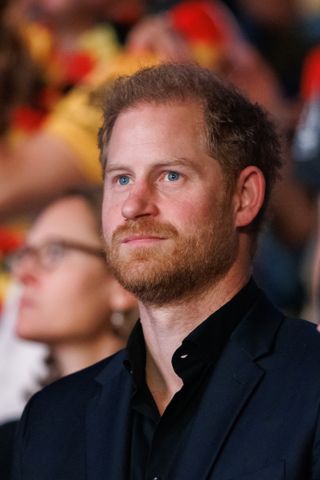 Prince harry wearing a navy suit and smiling