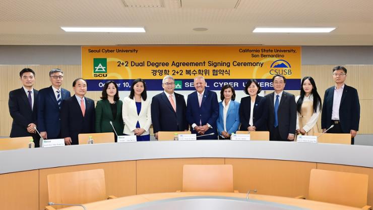 Seoul Cyber University President Lee Eun-joo, fifth from left, poses with Lee Sang-kyun, sixth from left, chairperson of the Shinil Education Foundation, and California State University of San Bernardino President Tomas D. Morales, seventh from left,  after signing a dual degree agreement at the university in Seoul, Oct. 10. Courtesy of Seoul Cyber University