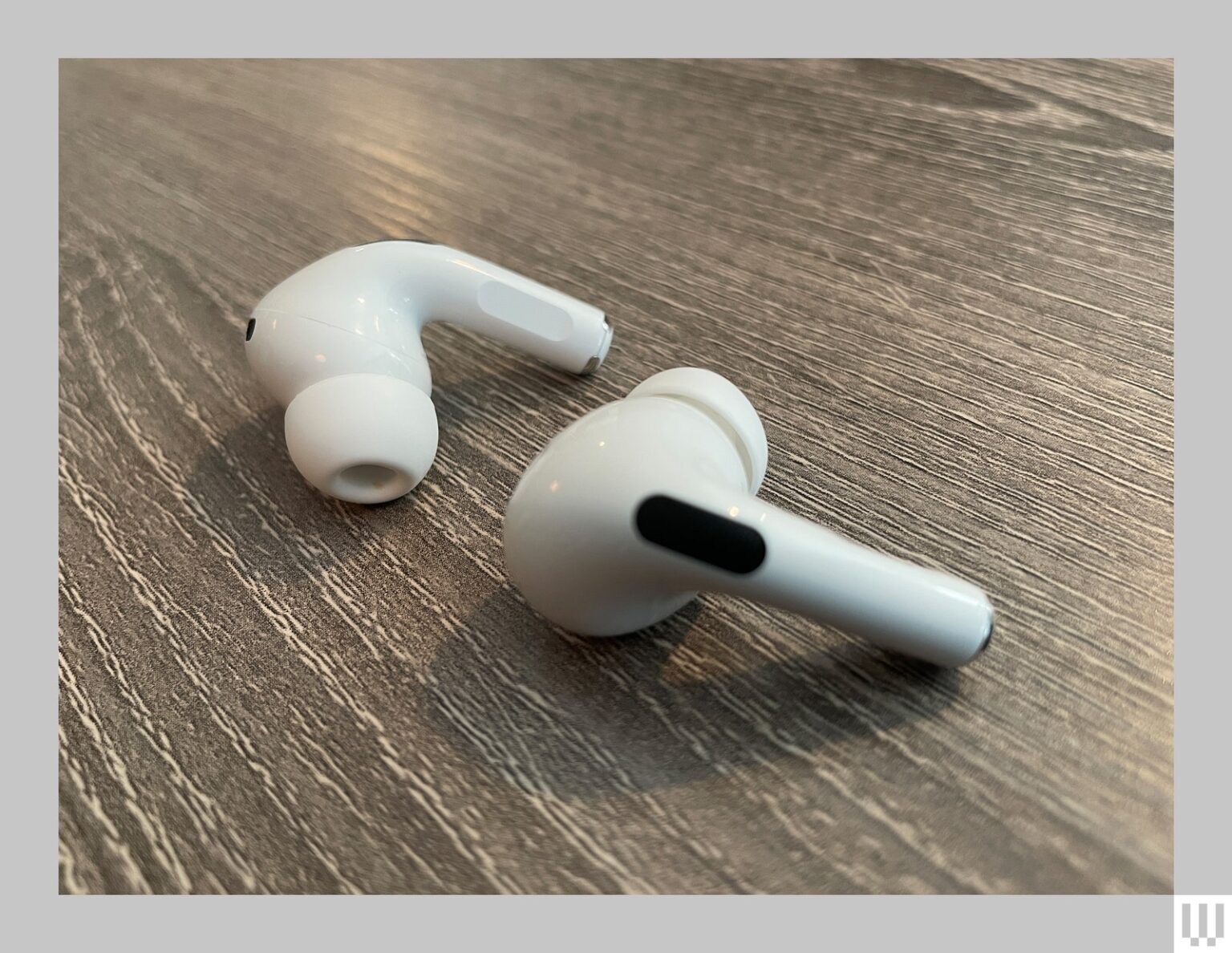 Apple AirPods Pro 2 two white earbuds sitting on a wooden surface