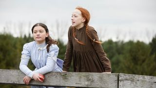 Amybeth McNulty as anne of greene gables standing on a bridge. in anne with an e