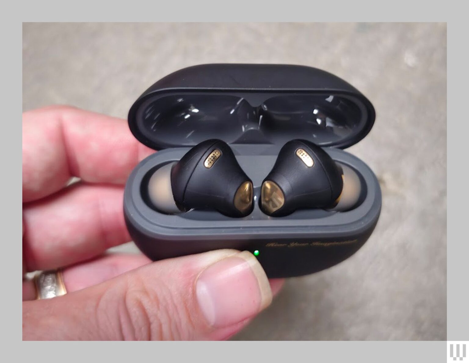 A hand holding the Soundpeats Capsule 3 Pro Plus earbuds in their black ovalshaped case