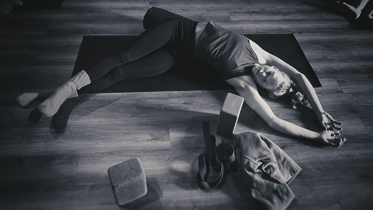 Black and white photo of a woman in a yin yoga pose known as Bananasana