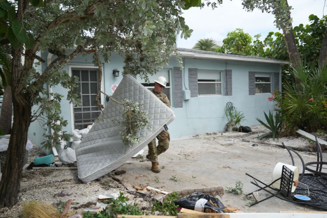 A Florida Army National Guard member moves a mattress in front of a house hit by Hurricane Helene in the Pass-A-Grille section of St. Petersburg on Monday.